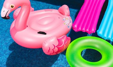 rosa aufblasbarer Flamingo und grüner aufblasbarer Ring liegen im Wasser