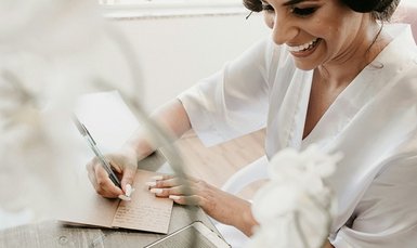 Lächelnde Person macht sitzt am Tisch mit einem Notizbuch und macht sich Notizen