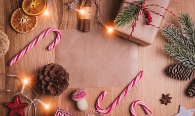 Lichterkette, Tannenzapfen und Geschenke liegen auf einem Tisch